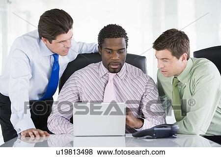 Three businessmen in a boardroom looking at laptop View Large Photo Image Stock Photo - Three businessmen in a boardroom looking at laptop. Fotosearch