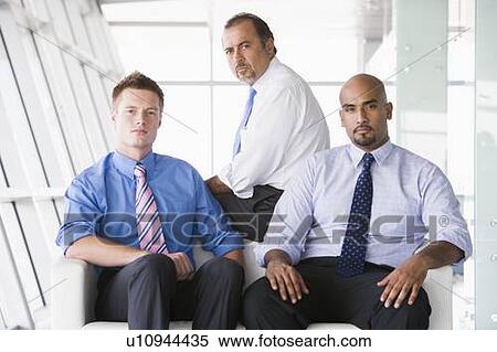 Stock Photography - Three businessmen sitting indoors (high key/selective focus). Fotosearch