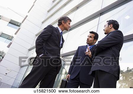 Three businessmen standing outdoors by building talking (high key/selective focus) View Large Photo Image Stock Image - Three businessmen standing outdoors by building talking (high key/selective focus). Fotosearch