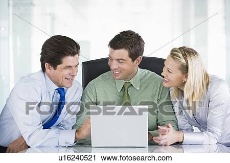 Three businesspeople in a boardroom looking at laptop smiling View Large Photo Image Stock Image - Three businesspeople in a boardroom looking at laptop smiling. Fotosearch