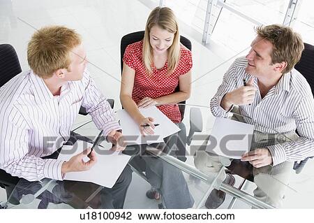 Three businesspeople in a boardroom looking at paperwork View Large Photo Image Stock Image - Three businesspeople in a boardroom looking at paperwork. Fotosearch