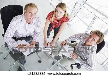 Three businesspeople in a boardroom with paperwork smiling View Large Photo Image Stock Photography - Three businesspeople in a boardroom with paperwork smiling. Fotosearch