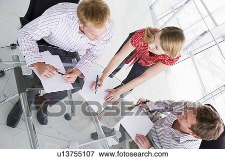 Stock Photo - Three businesspeople in boardroom with paperwork. Fotosearch