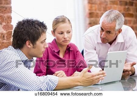 Picture - Three businesspeople in office with laptop. Fotosearch