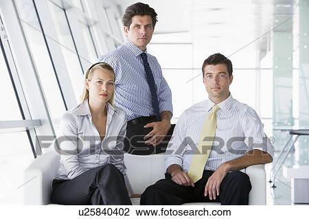 Three businesspeople sitting in office lobby View Large Photo Image Stock Image - Three businesspeople sitting in office lobby. Fotosearch