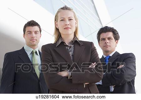 Three businesspeople standing outdoors by building View Large Photo Image Picture - Three businesspeople standing outdoors by building. Fotosearch