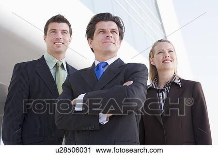 Three businesspeople standing outdoors by building smiling View Large Photo Image Stock Image - Three businesspeople standing outdoors by building smiling. Fotosearch
