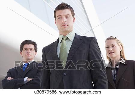 Stock Photograph - Three businesspeople standing outdoors by building. Fotosearch