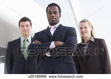 Stock Photography - Three businesspeople standing outdoors by building smiling. Fotosearch