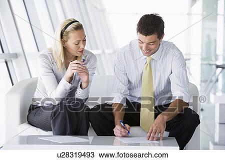 Two businesspeople sitting in office lobby talking and smiling View Large Photo Image Stock Image - Two businesspeople sitting in office lobby talking and smiling. Fotosearch