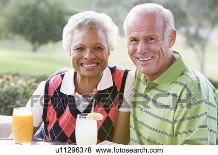Stock Photo - Couple Enjoying A Beverage By A Golf Course. Fotosearch