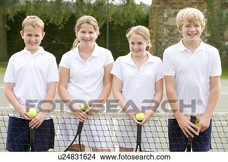 Picture - Four young friends with rackets on tennis court smiling. Fotosearch