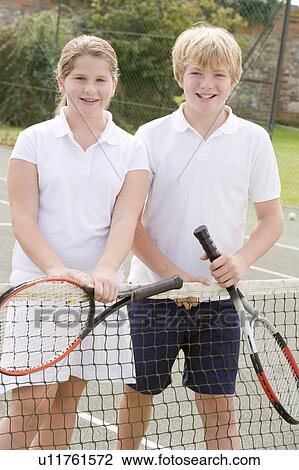 Two young friends with rackets on tennis court smiling View Large Photo Image Stock Image - Two young friends with rackets on tennis court smiling. Fotosearch