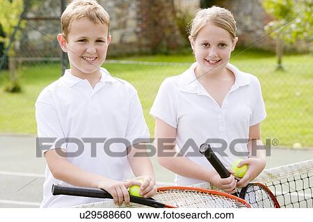 Two young friends with rackets on tennis court smiling View Large Photo Image Stock Image - Two young friends with rackets on tennis court smiling. Fotosearch