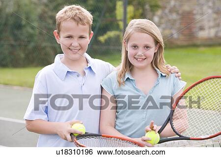 Two young friends with rackets on tennis court smiling View Large Photo Image Stock Photograph - Two young friends with rackets on tennis court smiling. Fotosearch