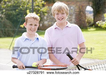 Two young male friends with rackets on tennis court smiling View Large Photo Image Stock Image - Two young male friends with rackets on tennis court smiling. Fotosearch