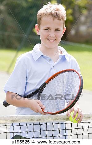 Picture - Young boy with racket on tennis court smiling. Fotosearch