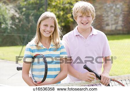 Young couple with rackets on tennis court smiling View Large Photo Image Stock Photo - Young couple with rackets on tennis court smiling. Fotosearch