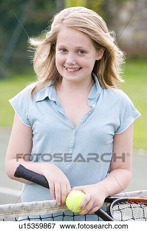 Young girl with racket on tennis court smiling View Large Photo Image Stock Photo - Young girl with racket on tennis court smiling. Fotosearch
