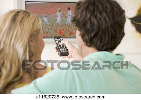 Couple in living room watching television View Large Photo Image Stock Photograph - Couple in living room watching television. Fotosearch