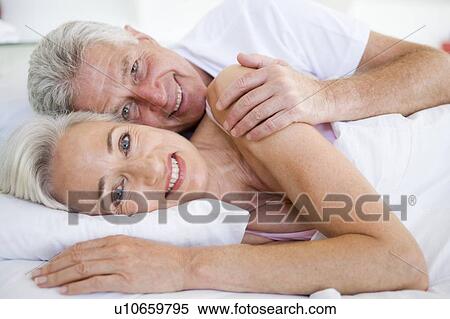 Couple lying in bed together smiling View Large Photo Image Stock Photography - Couple lying in bed together smiling. Fotosearch