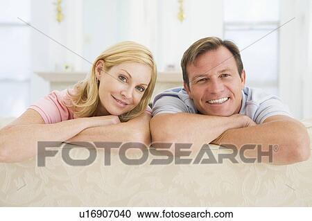 Couple relaxing in living room and smiling View Large Photo Image Stock Image - Couple relaxing in living room and smiling. Fotosearch