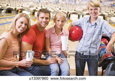 Stock Image - Family in bowling alley with drinks smiling. Fotosearch