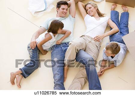 Family lying on floor by open boxes in new home smiling View Large Photo Image Stock Photography - Family lying on floor by open boxes in new home smiling. Fotosearch