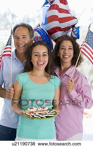 Stock Photo - Family outdoors on fourth of July with flags and cookies smiling. Fotosearch