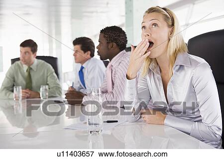 Stock Photo - Four businesspeople in boardroom with one businesswoman yawning. Fotosearch