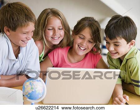 Picture - Group Of Young Children Doing Their Homework On A Laptop. Fotosearch