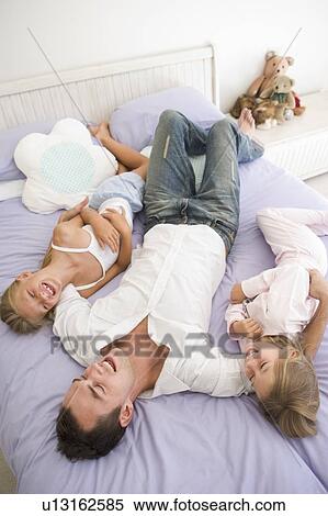 Man lying in bed with two young girls smiling View Large Photo Image Stock Photography - Man lying in bed with two young girls smiling. Fotosearch