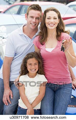 Stock Photo - Mother Father and young daughter shopping for a new car. Fotosearch