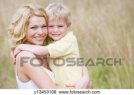 Stock Photo - Mother holding son outdoors smiling. Fotosearch