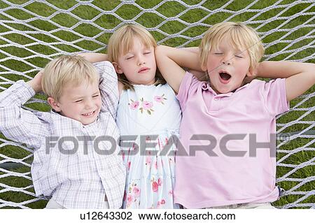 Stock Image - Three children relaxing and sleeping in hammock. Fotosearch