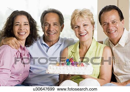 Stock Photo - Two couples in living room with cake smiling. Fotosearch