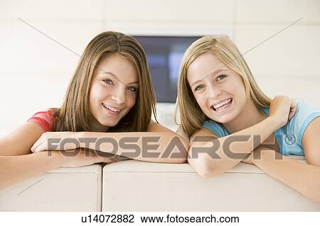 Stock Image - Two women in living room smiling. Fotosearch