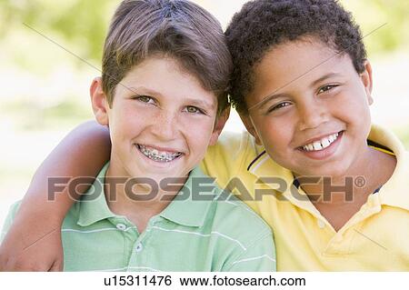 Stock Photograph - Two young male friends outdoors smiling. Fotosearch