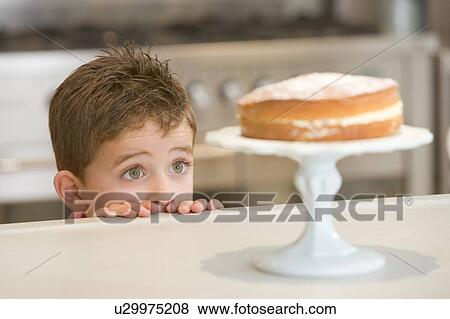 Young boy in kitchen looking at cake on counter View Large Photo Image Stock Photo - Young boy in kitchen looking at cake on counter. Fotosearch