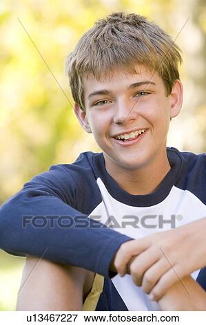 Stock Photo - Young boy sitting outdoors smiling. Fotosearch