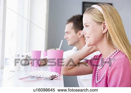 Stock Photography - Young couple having a cold drink in a cafeteria. Fotosearch