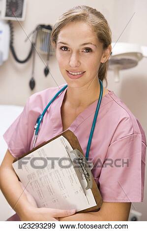 Stock Photo - Young Female Doctor In Scrubs, Holding A Clipboard. Fotosearch