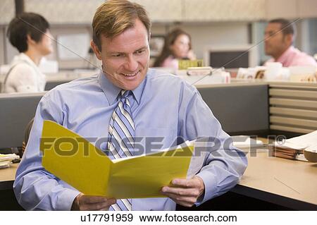 Stock Photo - Businessman in cubicle with folder smiling. Fotosearch