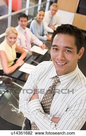Businessman with four businesspeople at boardroom table in background View Large Photo Image Stock Image - Businessman with four businesspeople at boardroom table in background. Fotosearch