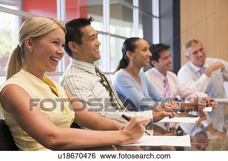 Stock Photograph - Five businesspeople at boardroom table smiling. Fotosearch