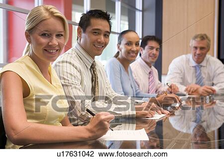 Stock Image - Five businesspeople in boardroom smiling. Fotosearch
