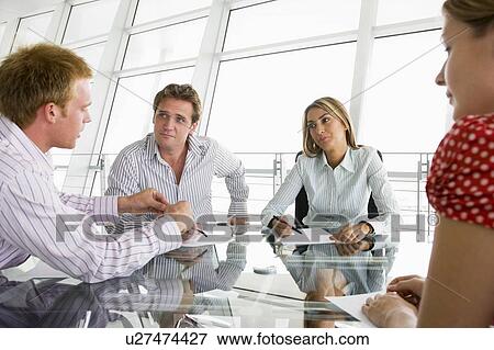 Stock Photo - Four businesspeople in a boardroom with paperwork. Fotosearch