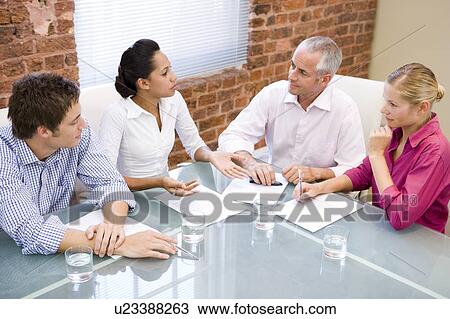 Stock Image - Four businesspeople in boardroom meeting. Fotosearch