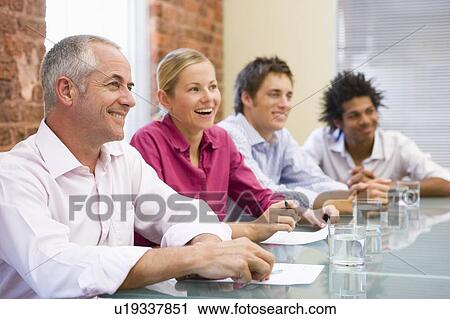 Four businesspeople in boardroom smiling View Large Photo Image Stock Image - Four businesspeople in boardroom smiling. Fotosearch