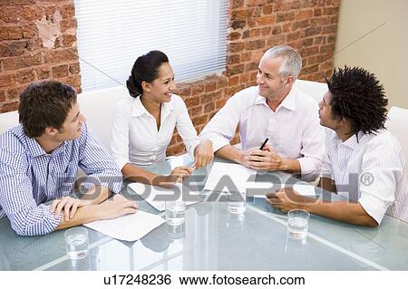 Stock Photograph - Four businesspeople in boardroom smiling. Fotosearch